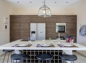 Une cuisine moderne dotée d’un îlot central, d’un meuble à vin et de tabourets de bar.