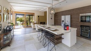 Une cuisine spacieuse dotée d’un îlot central, d’appareils électroménagers modernes et d’un grand coin repas avec des tabourets de bar.