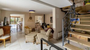 Un vaste espace de vie comprenant un escalier, un coin repas et une vue sur l’extérieur.
