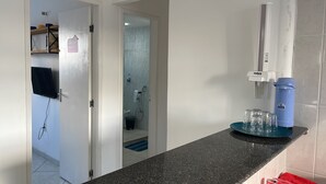 A hotel room with a kitchenette, a bathroom with a shower, and a small dining area. - Loft CeoPremium 2 | near beaches and shopping malls (Salgado Filho Aracaju)