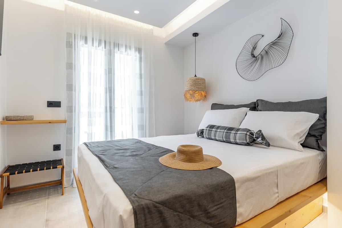 A modern bedroom with a bed, a bench, a hat, and a wall art piece.