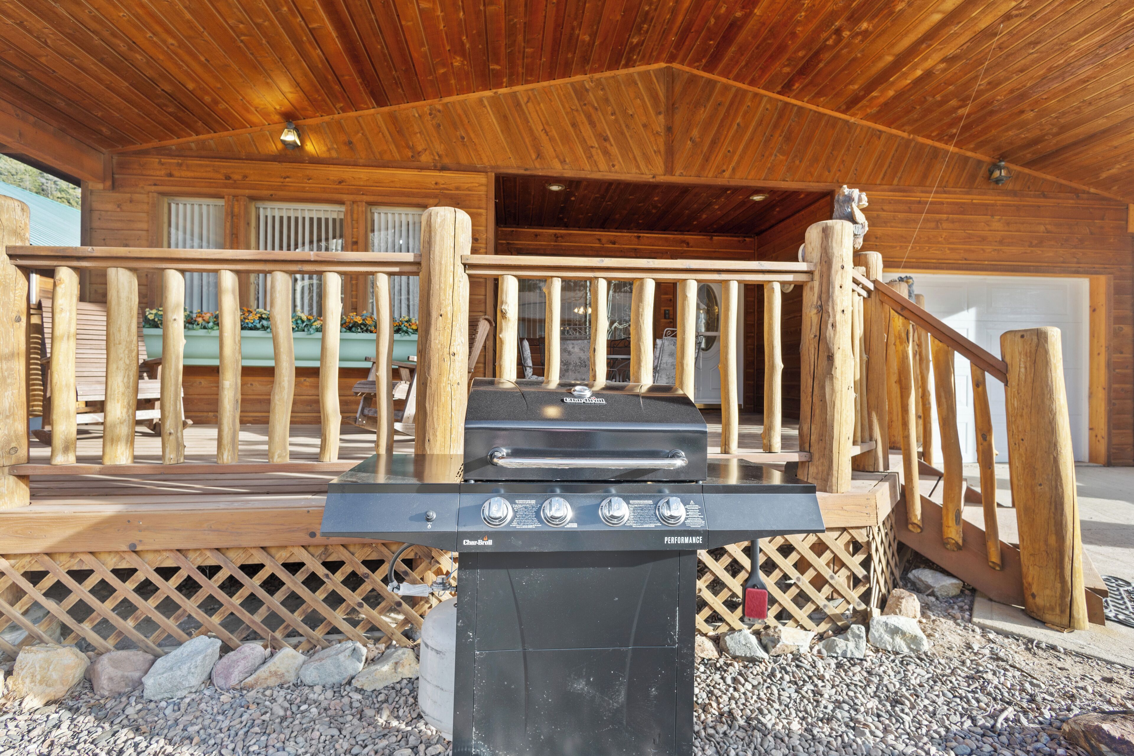 Une terrasse en bois avec un barbecue devant une cabane.