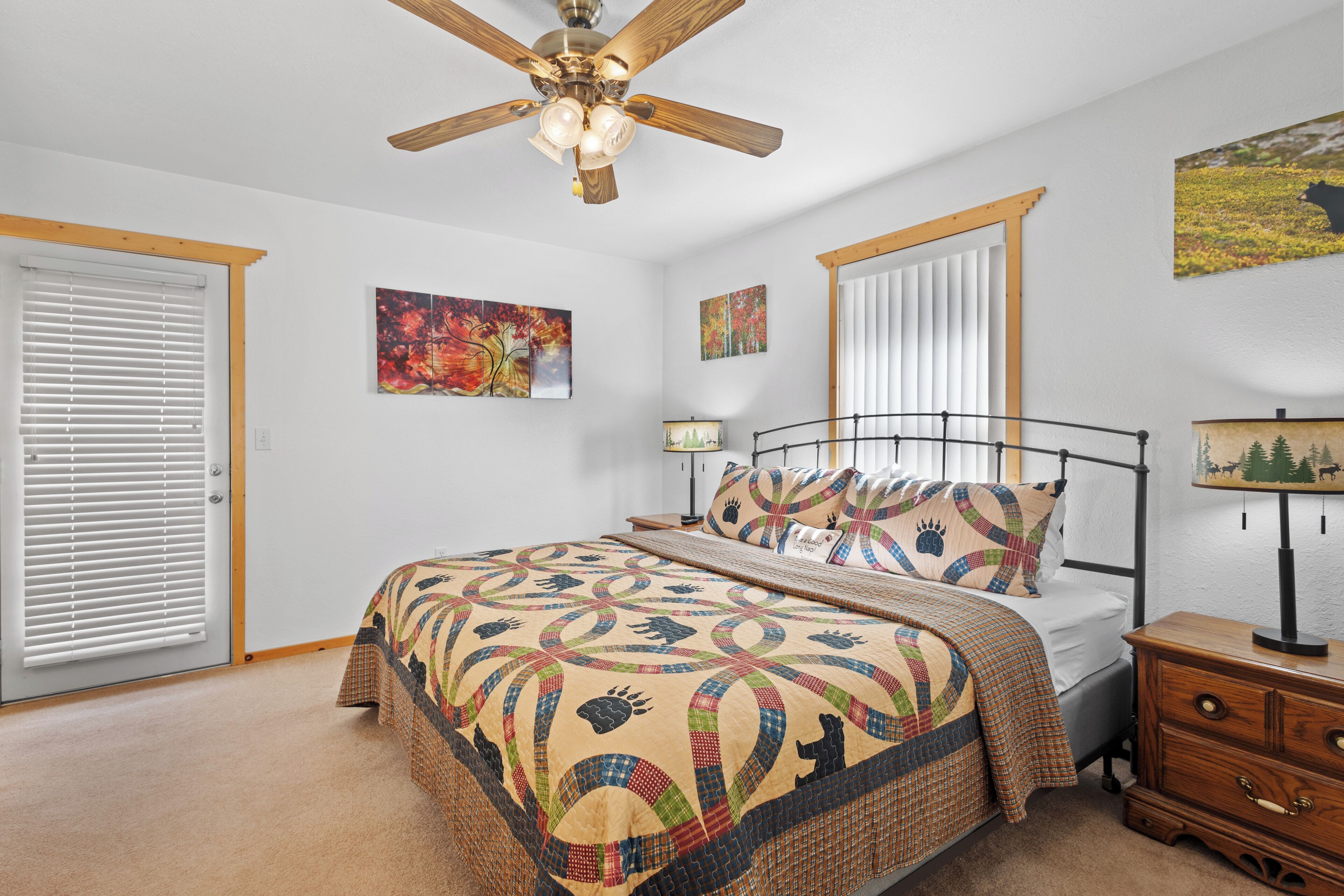 A bedroom with a bed, a nightstand, a ceiling fan, and artwork on the walls.