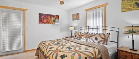 A bedroom with a bed, a nightstand, a ceiling fan, and artwork on the walls.