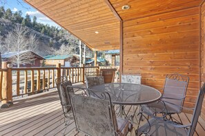A wooden deck with metal chairs and a table, overlooking a mountainous area with buildings. - "Heaven's Hideaway" 3 Bedroom, In Town, Close to River, Free WIFI (Red River)