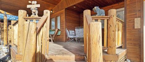 A wooden cabin with a wooden staircase leading to a covered porch area.
