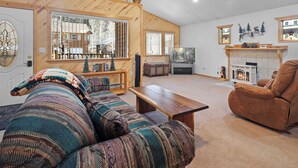 Un salón acogedor con techo de madera, chimenea, sofá y televisor.