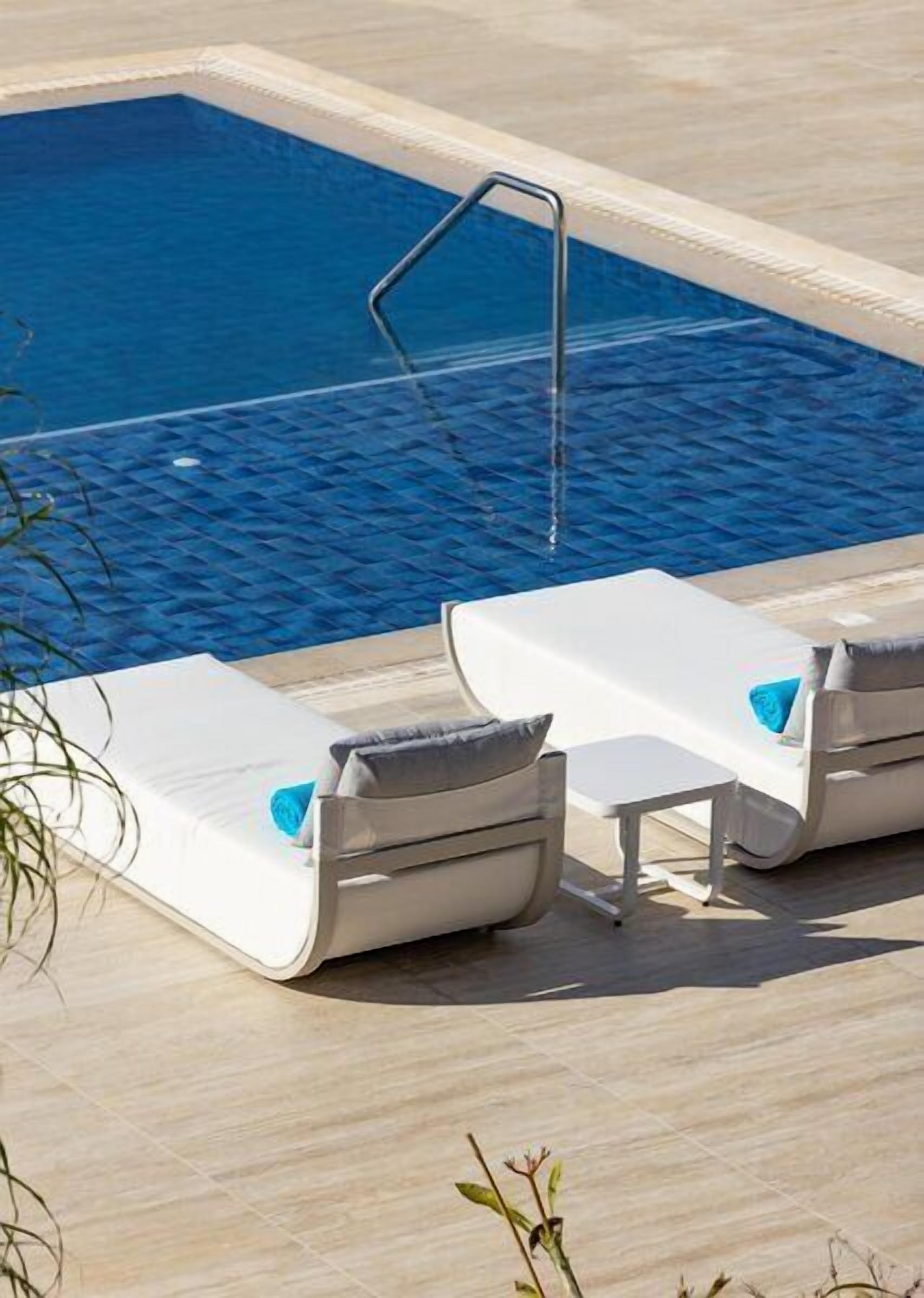 Un área de piscina con dos sillones de descanso y una escalera de piscina.