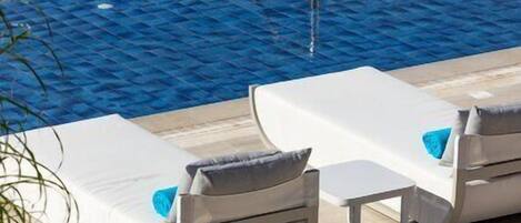 Un área de piscina con dos sillones de descanso y una escalera de piscina.