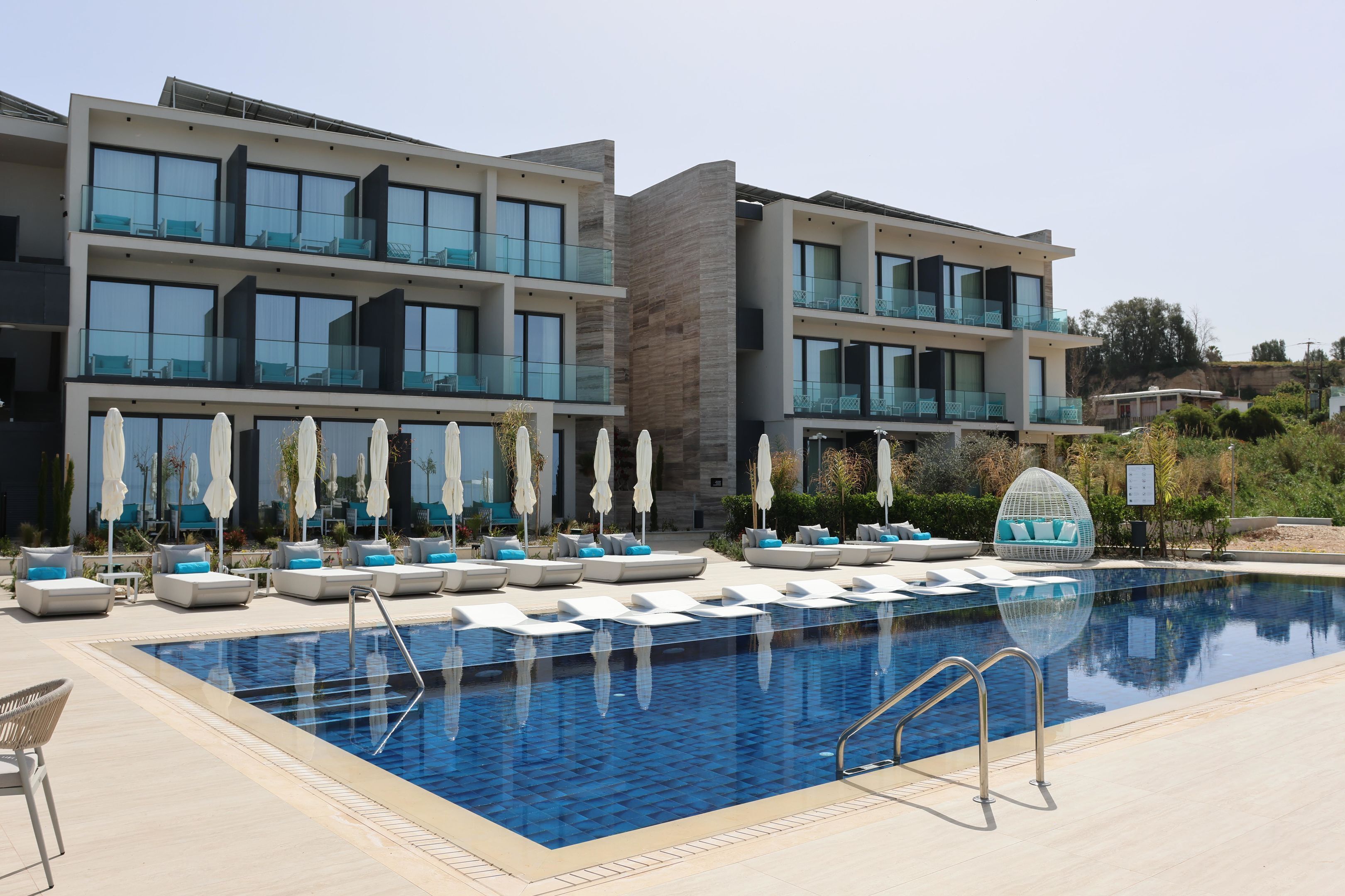 A modern hotel with a swimming pool, multiple balconies, and outdoor seating areas.
