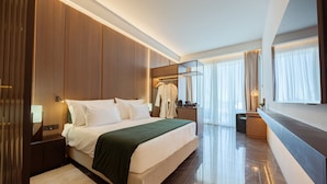 Una habitación de hotel moderna con una cama grande, un tocador con espejo y una zona de estar.