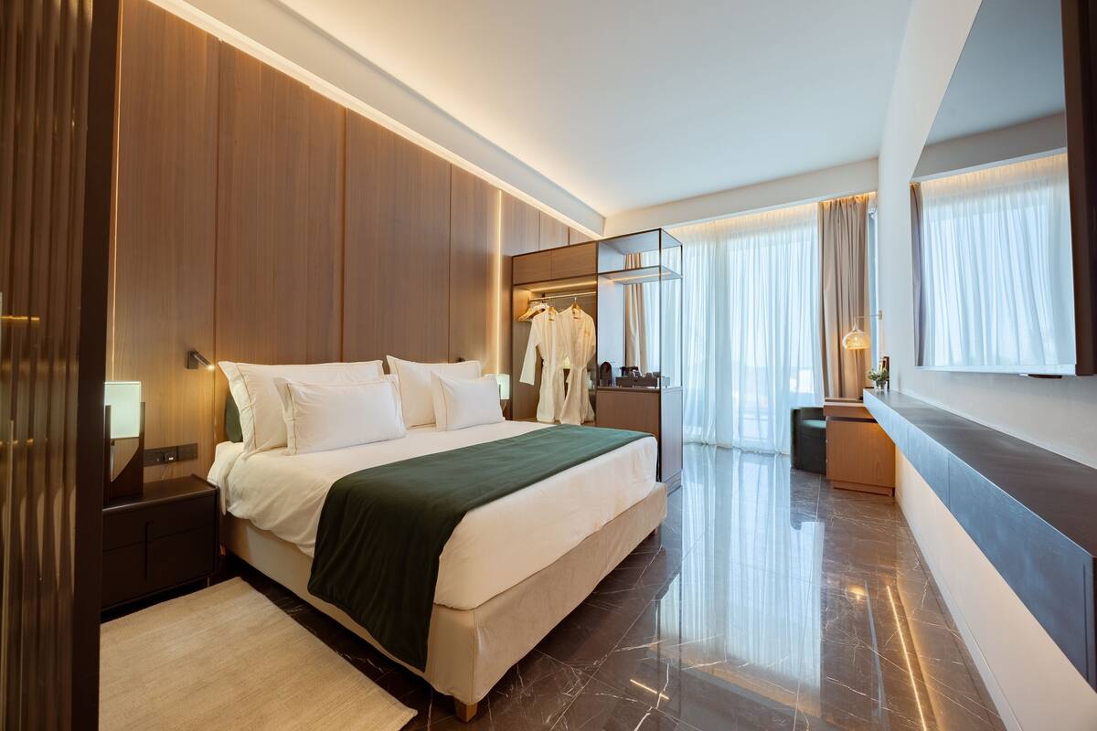 Una habitación de hotel moderna con una cama grande, un tocador con espejo y una zona de estar.