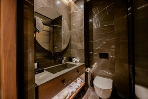 Egy modern fürőszoba, amelyben nagy tükör, mosdókagyló, WC és zuhanyzó található.