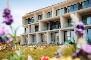 Un hotel moderno con varios balcones, un jardín cuidado y zonas de estar al aire libre.