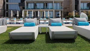 Un hotel moderno con zona de piscina, sillones de descanso y sombrillas.