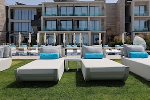 Un hotel moderno con zona de piscina, sillones de descanso y sombrillas.