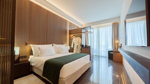 Une chambre d’hôtel moderne avec un grand lit, une coiffeuse avec un miroir et un dressing.
