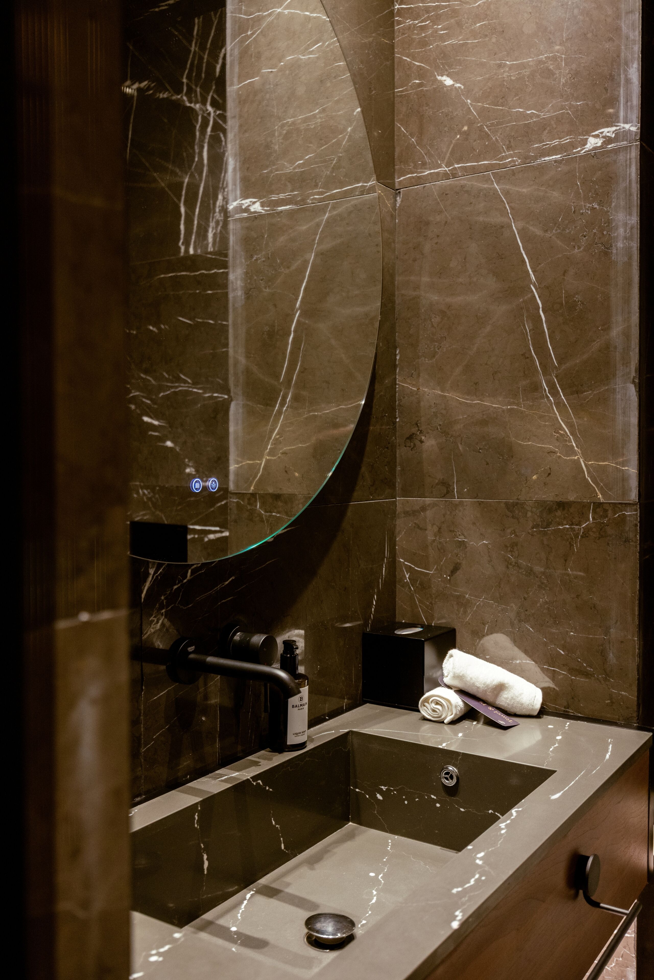 A modern bathroom with a marble sink, a large mirror, and a towel on the counter.