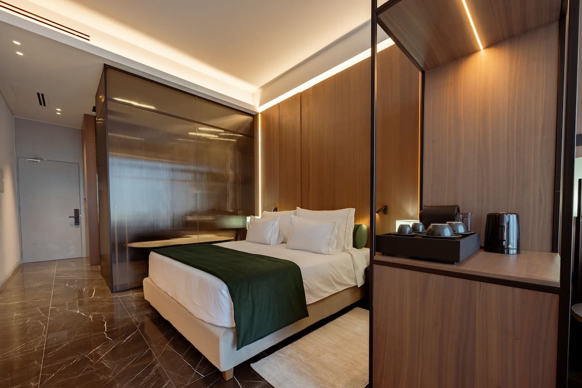 Una habitación de hotel moderna con una cama grande, un armario de madera y una pequeña zona de kitchenette.