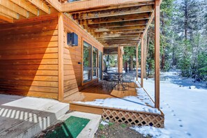A wooden cabin with a covered porch and a view of a snowy forest. - Apartment (Estes Park)