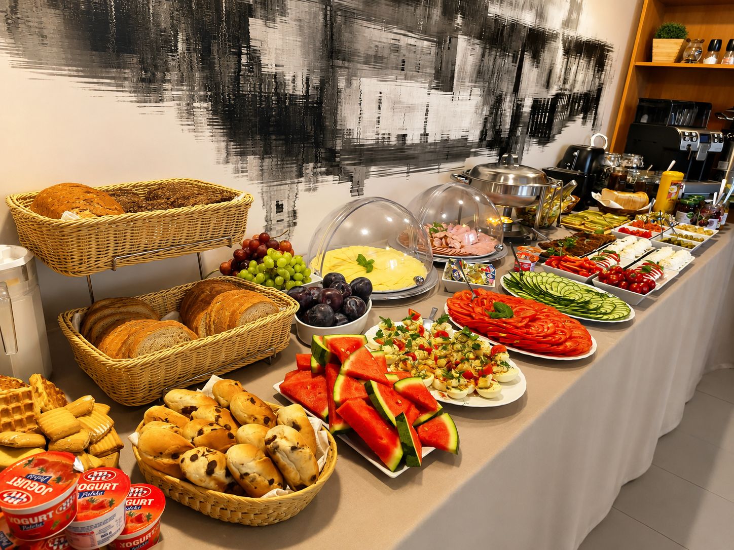 Ein Buffet mit verschiedenen Speisen, darunter Brot, Obst, Gemüse und Milchprodukte.