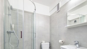 Une salle de bain moderne avec une douche à parois de verre, des toilettes et un lavabo avec un miroir au-dessus.