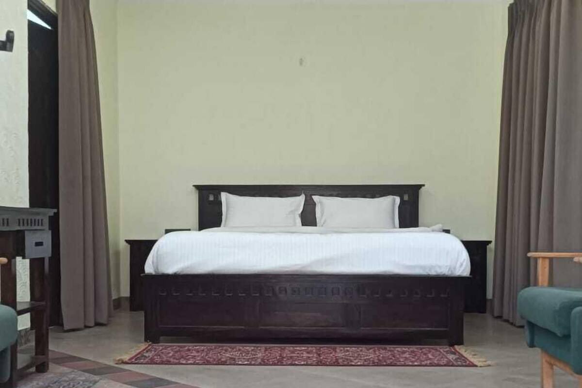 Ein Schlafzimmer mit Bett, Vorhängen, Deckenventilator und einem gemusterten Boden.