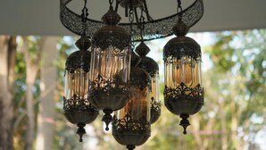 Un lustre orné de motifs métalliques complexes et doté de plusieurs abat-jour en verre.