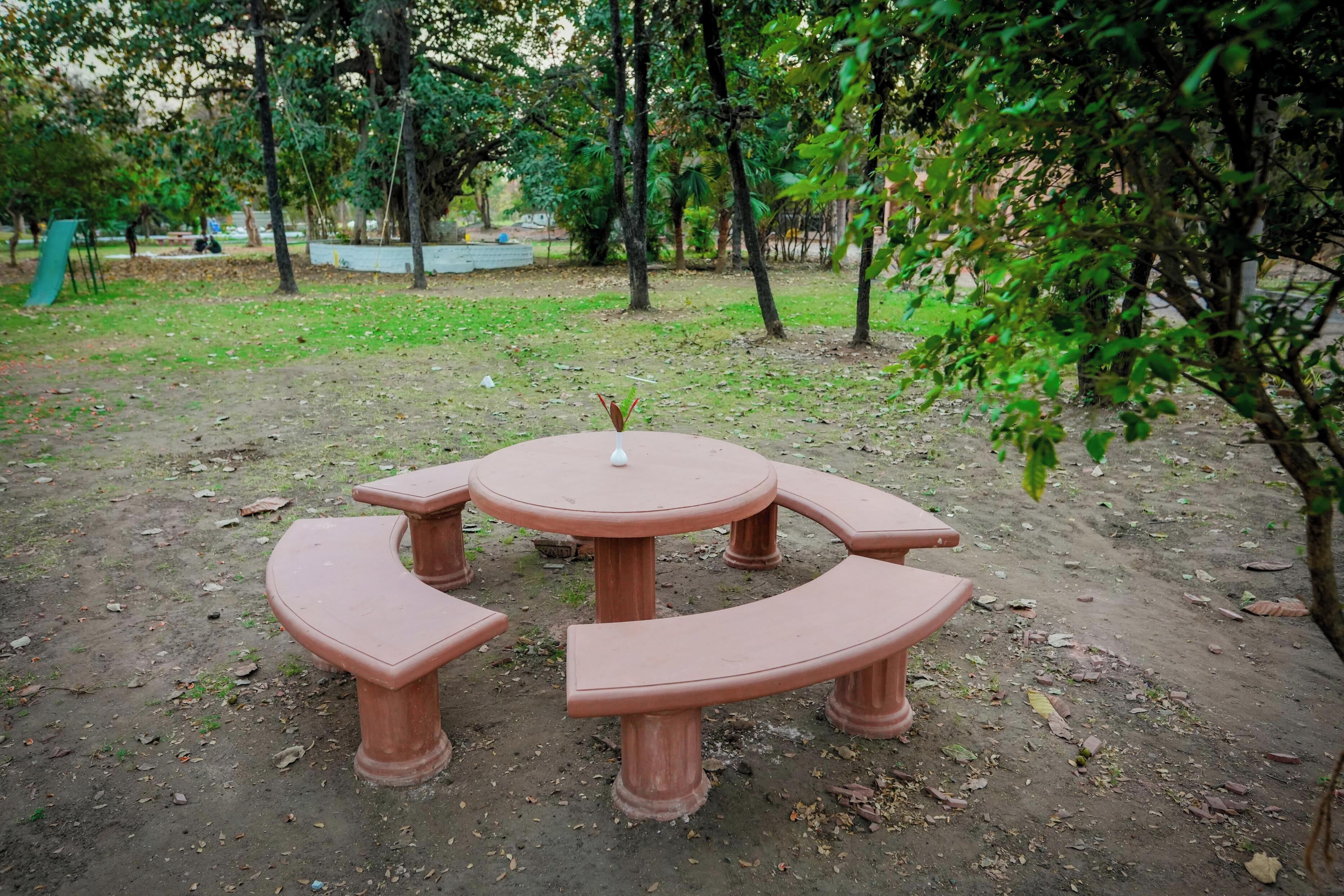 A round table with benches in a park setting.