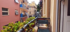 A narrow urban alleyway with buildings on either side, featuring balconies with railings and some greenery. - Super Central Rooms (Cagliari)