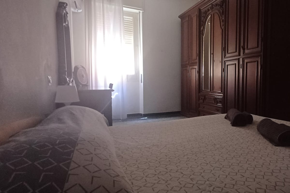 A hotel room with a bed, a wardrobe, and a painting on the wall.