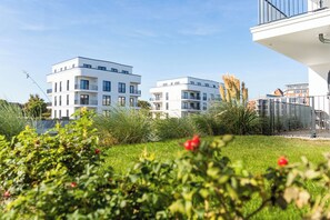 Un edificio residenziale moderno con tetto piatto, diversi balconi e un prato curato.