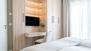 Un dormitorio moderno con una cama, un escritorio con televisor de pantalla plana y una silla.