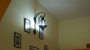 Una stanza con un divano, una lampada a parete e quadri appesi.