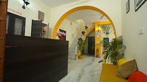 Un'area di accoglienza con pavimento in marmo, una reception, una scala e piante in vaso.