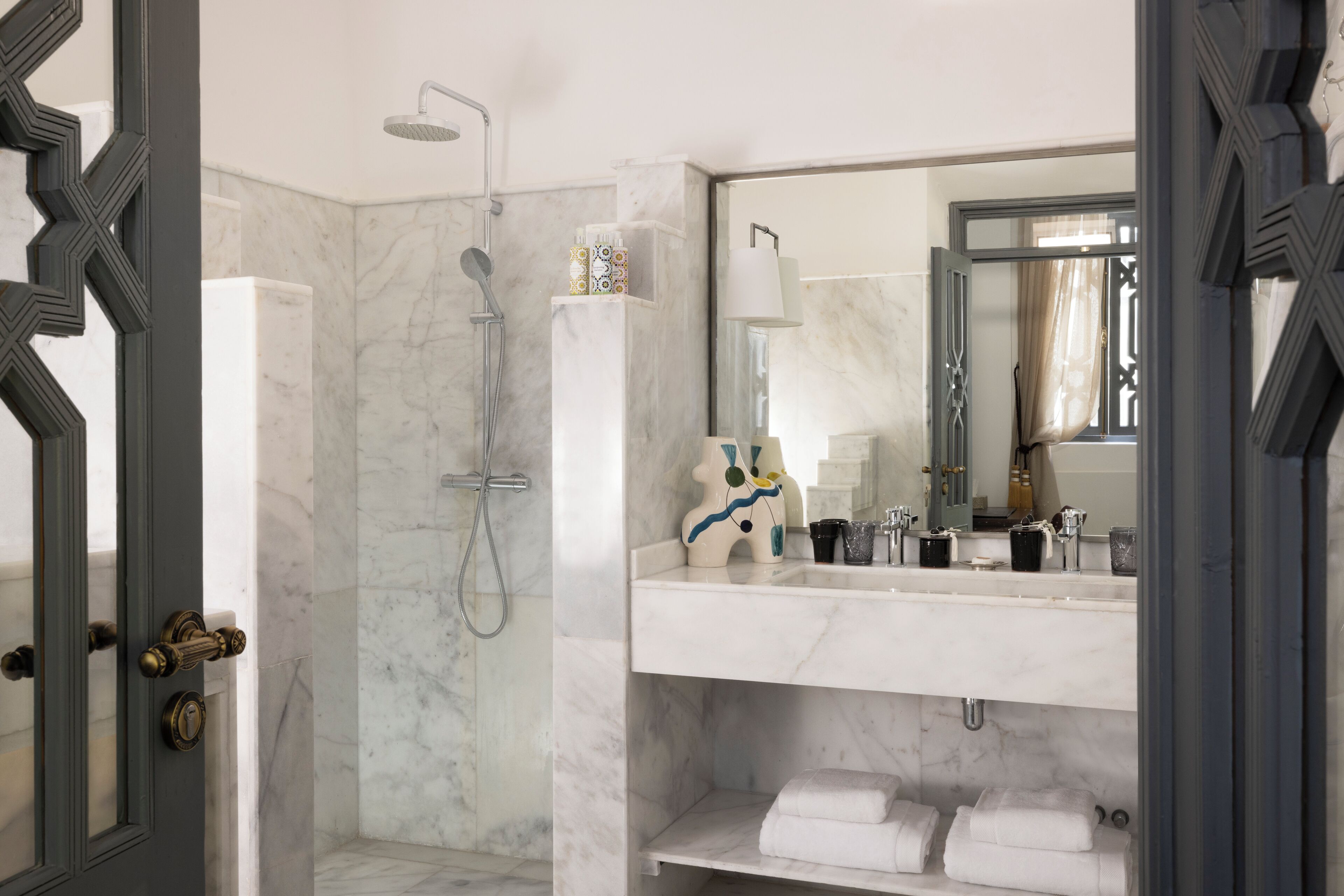 A modern bathroom with a walk-in shower, a marble sink, and a large mirror.