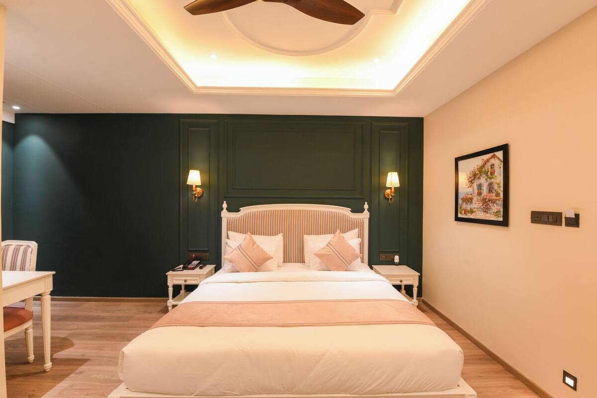 A neatly arranged bedroom with a large bed, two bedside tables, a desk, and a ceiling fan.