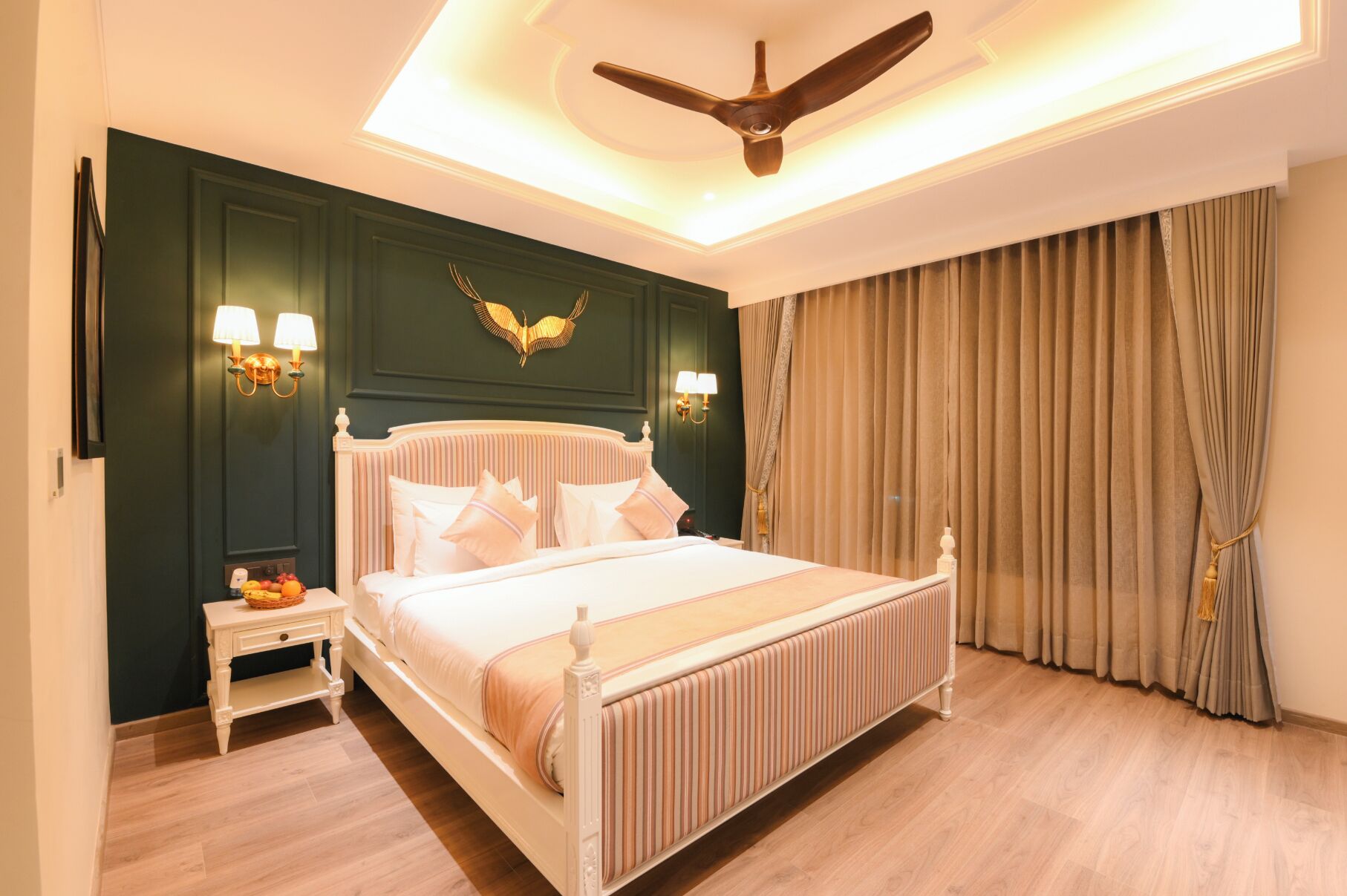 A neatly arranged bedroom with a large bed, a nightstand, a ceiling fan, and a wall-mounted light fixture.