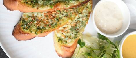A plate with garlic bread, a salad, and two dipping sauces.