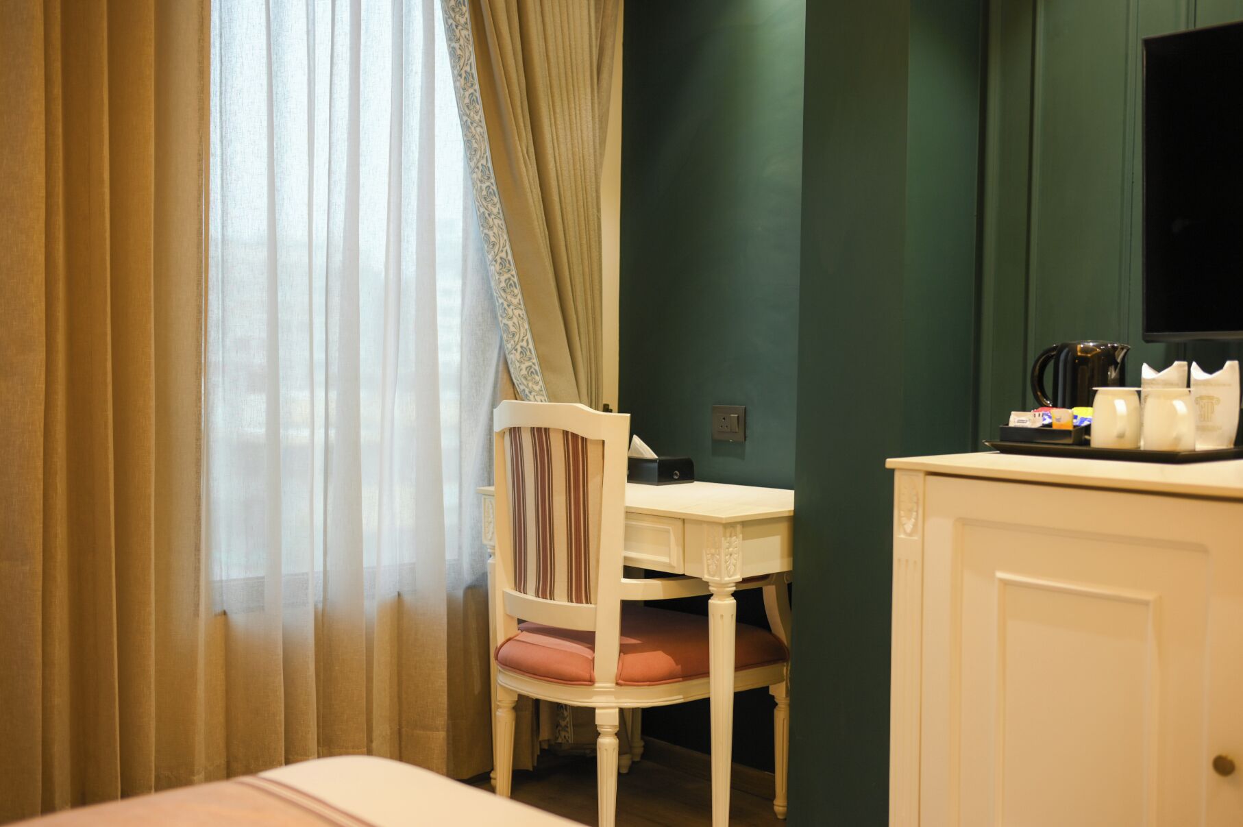 Een hotelkamer met een bed, een stoel, een bureau met telefoon en een minibar.