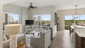 Una sala de estar moderna con un sofá, una mesa de centro, un televisor y un balcón con vistas a la ciudad.