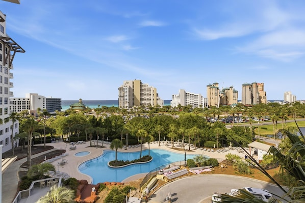 A resort with a swimming pool, palm trees, and high-rise buildings in the background.