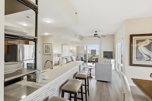 A modern kitchen with a marble countertop, stainless steel appliances, and a bar area with stools.
