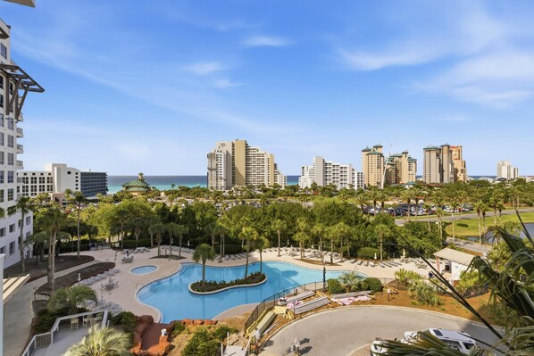 A resort with a swimming pool, palm trees, and high-rise buildings in the background.