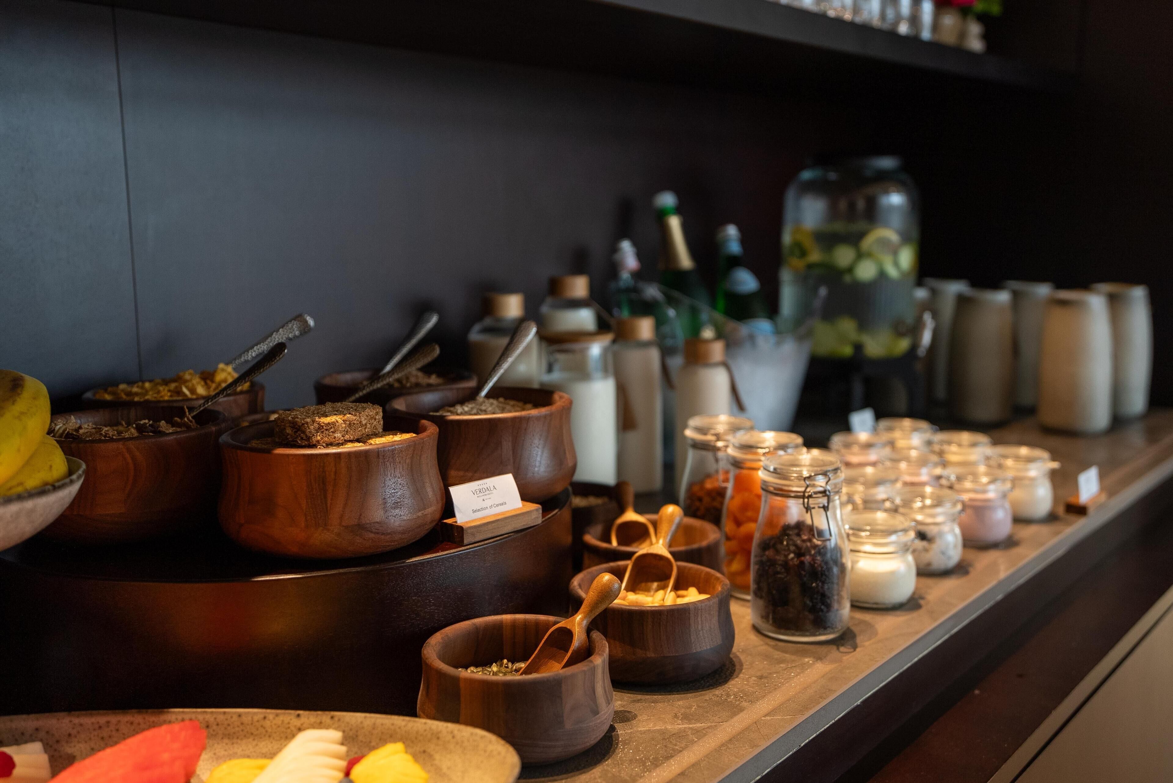 A buffet area with various food items and condiments displayed in wooden bowls and jars.