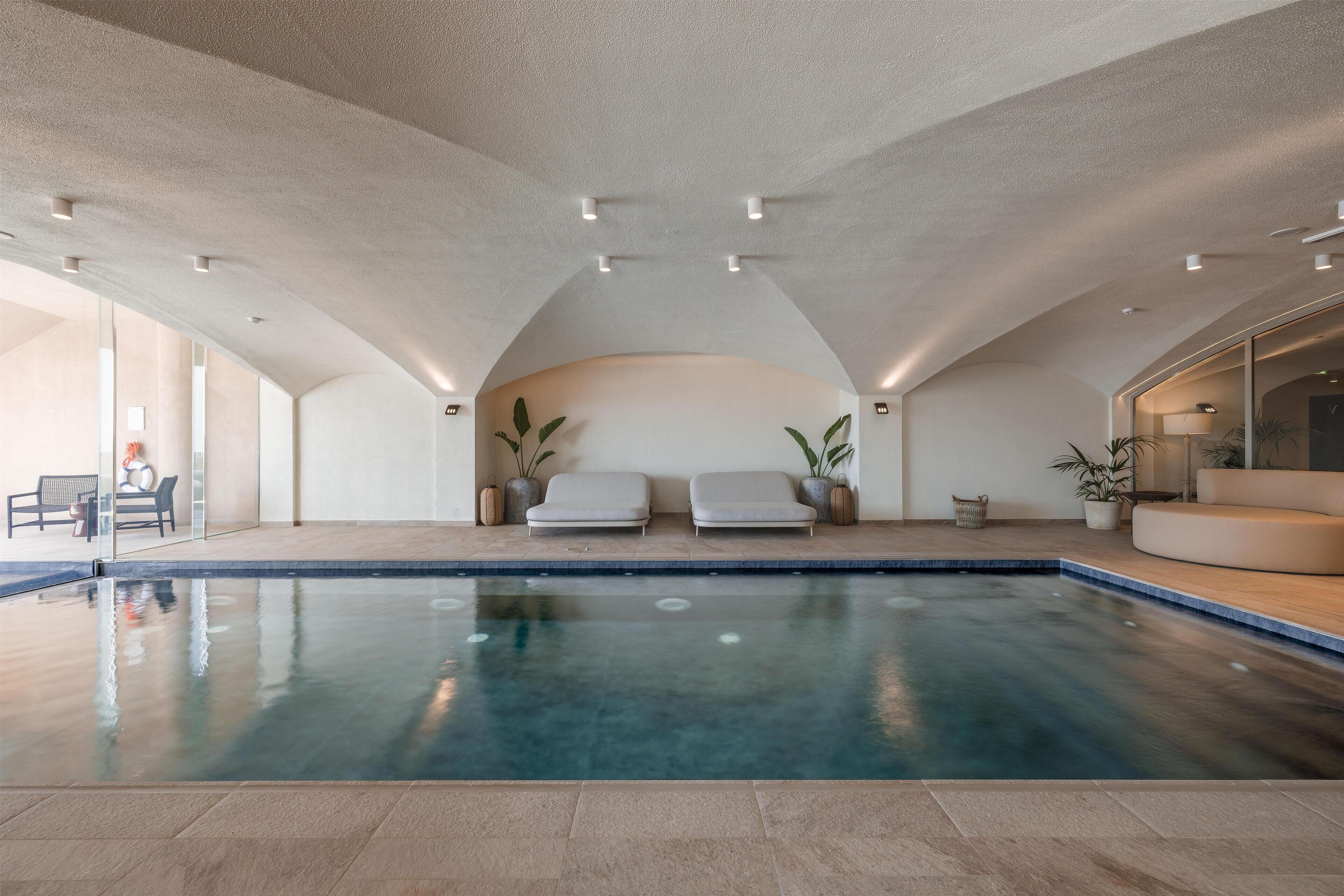 A spacious indoor swimming pool with a high ceiling and recessed lighting.