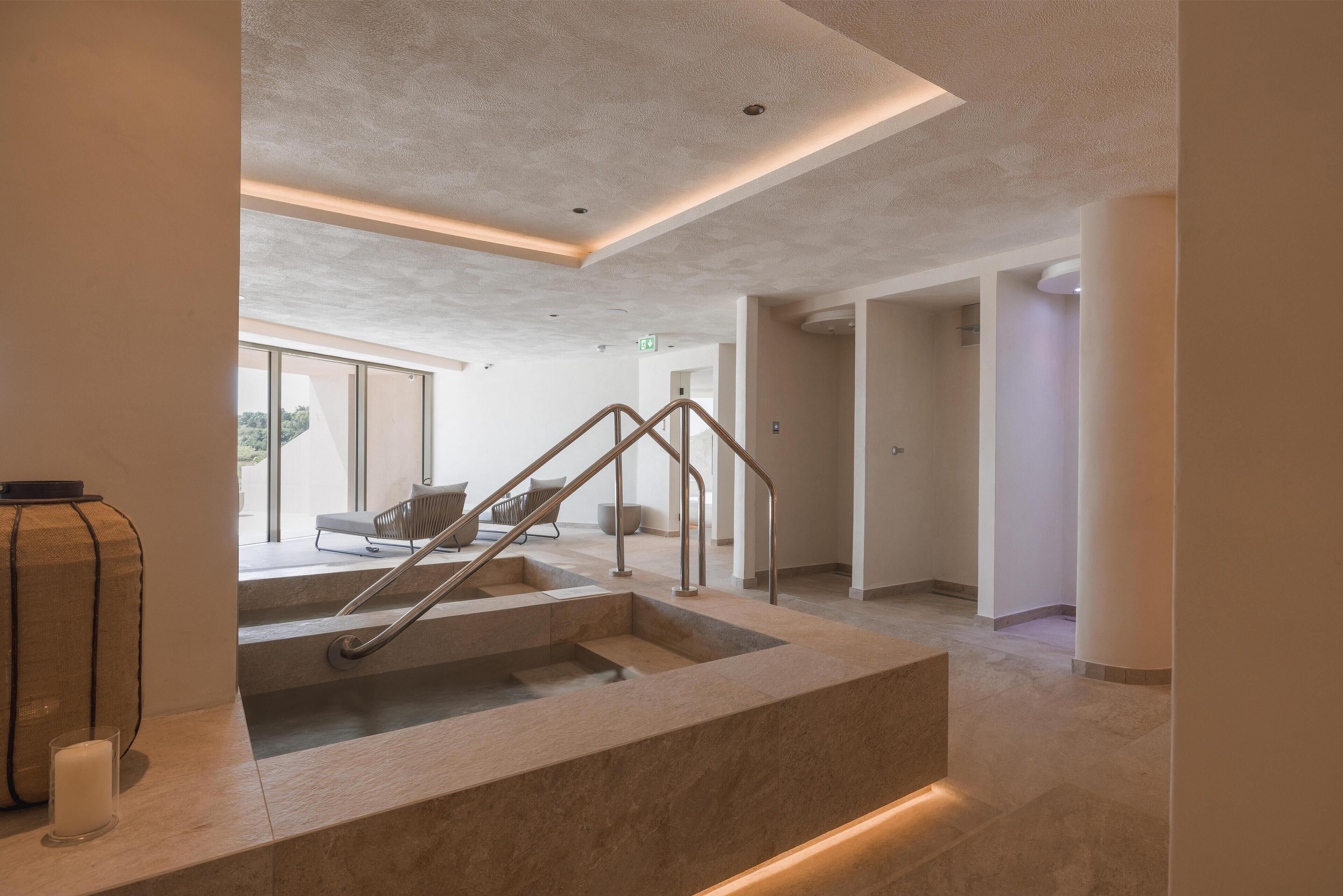 Un interno moderno con una scala in pietra, arredamento minimalista e vista sull'esterno.