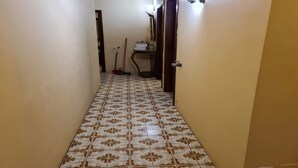 Un pasillo estrecho con baldosas de diseño en el suelo, una puerta a la derecha y un aplique en la pared.