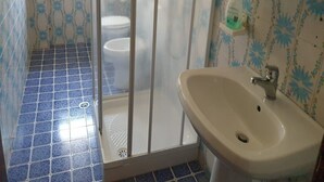 Un baño con paredes de azulejos azules, un lavabo blanco y un inodoro.