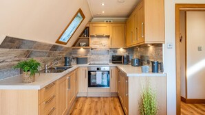 A modern kitchen with wooden cabinets, a built-in oven, and a microwave. - Wonderful private villa for 4 guests with WIFI, TV, balcony and panoramic view (Kilfinnan)